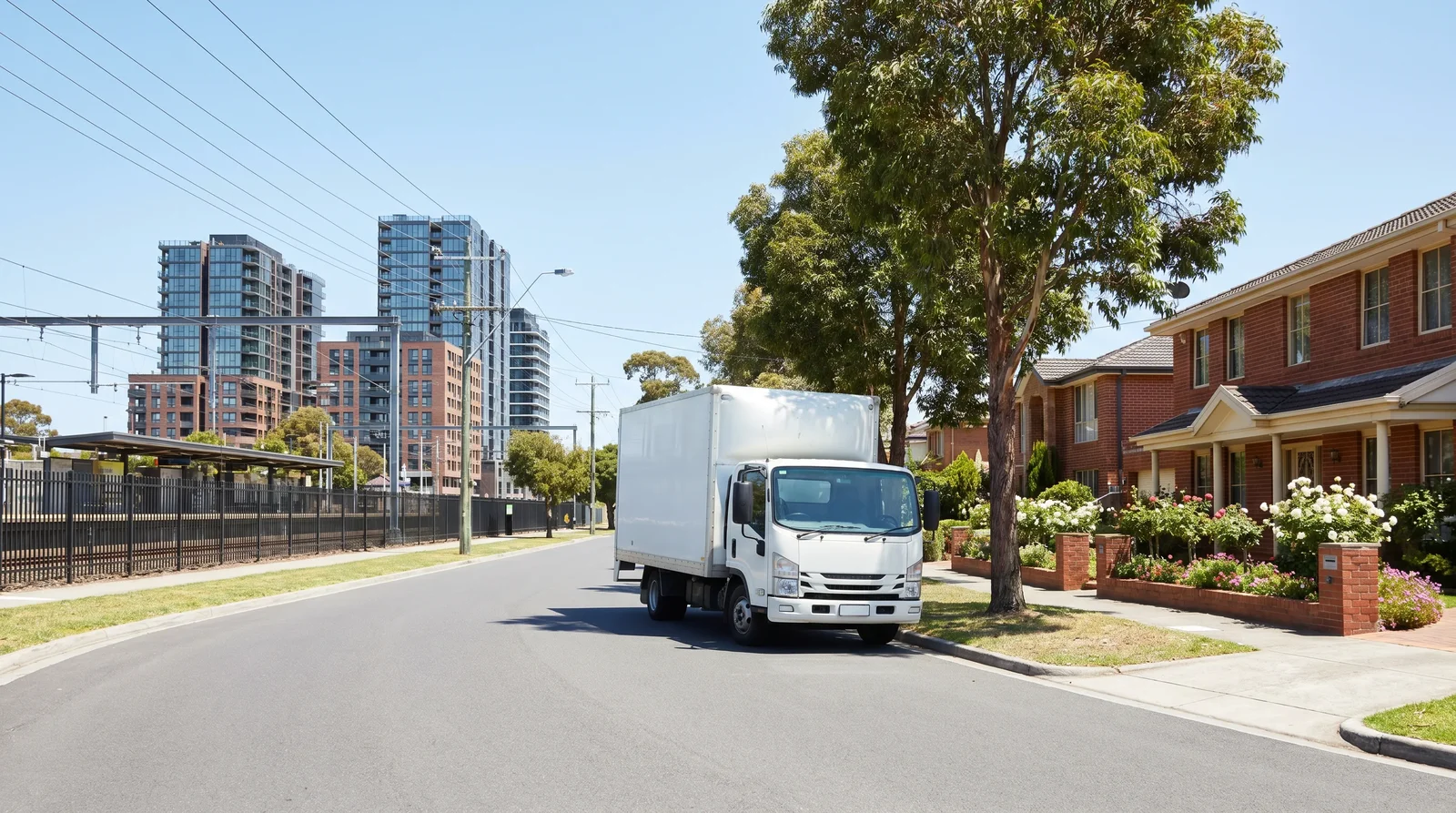A removal truck on a Melbourne south-east street with apartment towers and large family homes behind
